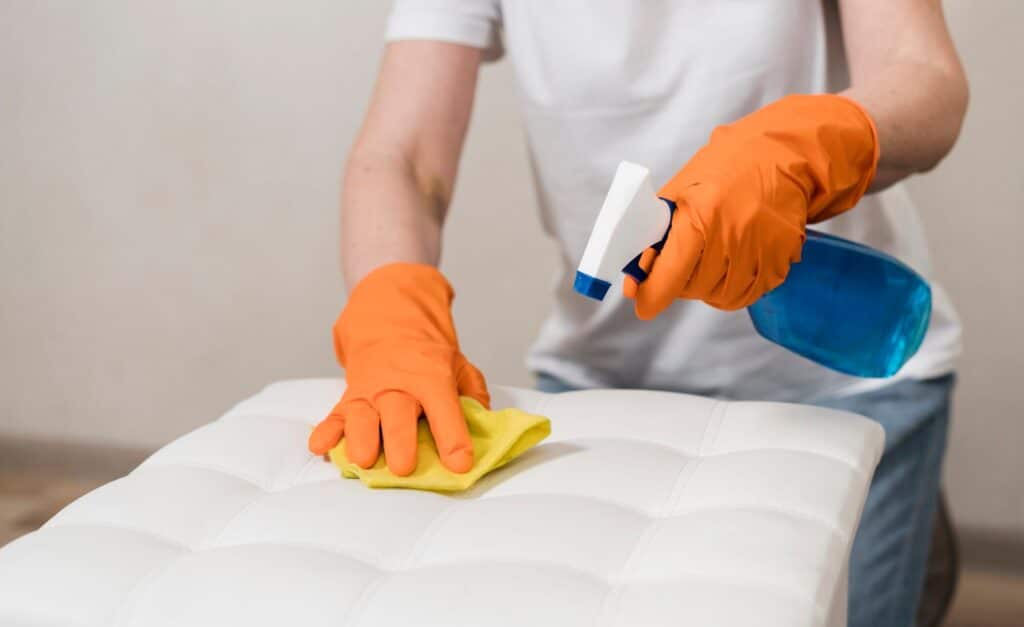Woman with rubber gloves cleaning bedroom